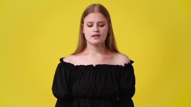 黄色の背景で何かを求めている1人の女の子の4Kビデオ 感情の概念 — ストック動画