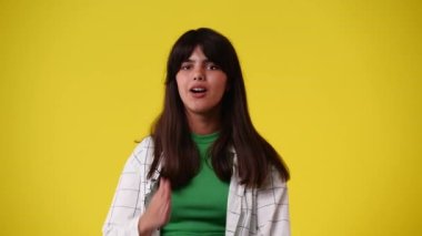Sarı arka planda hava öpücüğü gönderen bir kızın 4K videosu. Aşk duygusu kavramı.