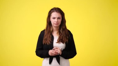 4K video, sarı arka planda büyük gözleri olan bir kız el kaldırıyor. Duyguların kavramı.