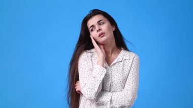 Mavi arka planda başı ağrıyan bir kızın 4K videosu. Duygu kavramı.