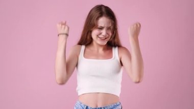 4K video 'da, pembe arka planda büyük gözleri olan bir kız el kaldırıyor. Duyguların kavramı.