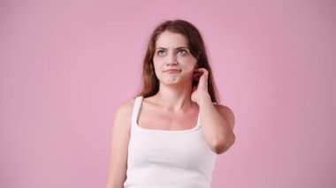 Pembe arka planda düşünen genç bir kadının 4K videosu. Düşünce kavramı.