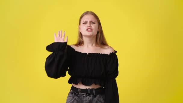 黄色の背景で意見の不一致を示す1人の少女の4Kビデオ 感情の概念 — ストック動画