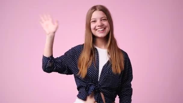 一个女孩在粉色背景下挥手打招呼的4K视频 感情的概念 — 图库视频影像