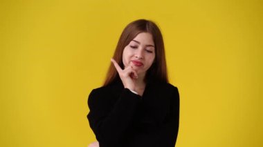 Sarı arka planda kurnaz yüz ifadesi olan bir kızın 4K videosu. Fikirleri olan kız kavramı.