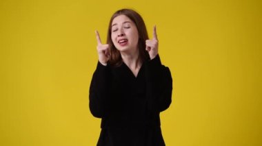 Kamerayı işaret eden ve sarı arka planda başparmağını gösteren 4K video. Duyguların kavramı.