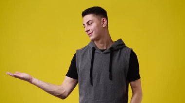 Sarı arka planda baş parmağını gösteren bir adamın 4K videosu. Duyguların kavramı.