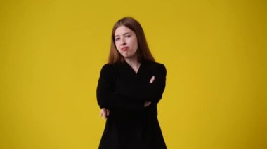 Sarı arka planda negatif yüz ifadesi olan hoş bir kızın 4K videosu. Duyguların kavramı.