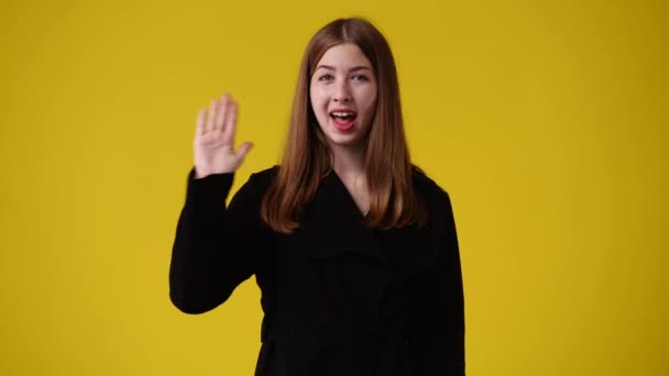 黄色い背景にこんにちはを振る可愛い女の子の4K動画 感情の概念 — ストック動画