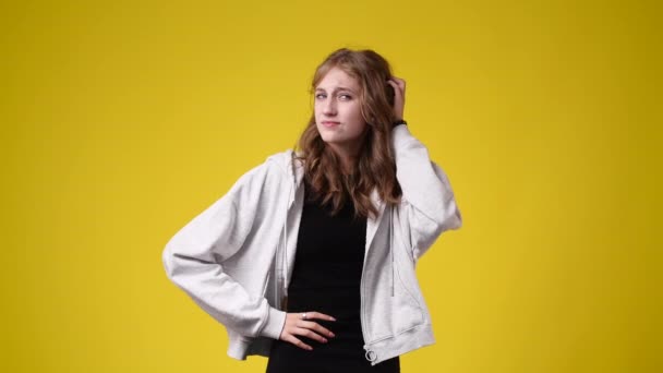 4K视频 一个女孩四处张望 用黄色背景触摸她的头发 情绪的概念 — 图库视频影像
