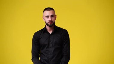 Yakışıklı bir adamın sarı arka planda el kol hareketi yaptığı 4K video. Duyguların kavramı.