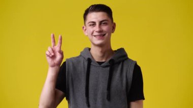 Sarı arka plandaki bir video için poz veren bir adamın 4K videosu. Duyguların kavramı.