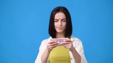 Telefonunda oyun oynayan tatlı bir kızın 4K yavaş çekim videosu. Duyguların kavramı.