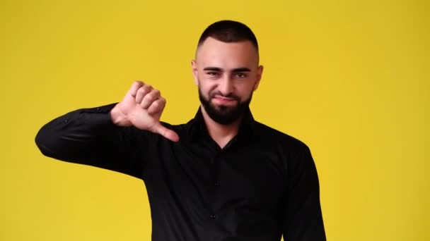 一个男人在黄色背景下显示大拇指的4K视频 负面情绪的概念 — 图库视频影像