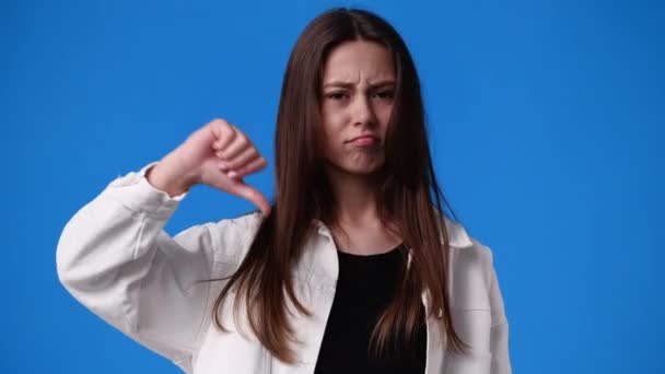 青い背景に親指を示す少女の4Kスローモーションビデオ 負の感情の概念 — ストック動画