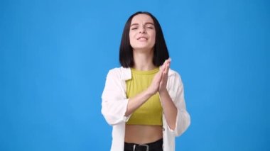 Heyecanlı bir kızın mavi arka planda el çırpışının 4K yavaş videosu. El çırpma kavramı.
