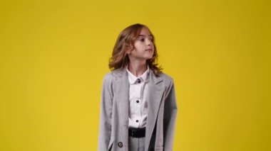 Bir kızın sağa sola baktığı ve sarı arka planda solu işaret ettiği 4k yavaş çekim videosu. Duyguların kavramı.