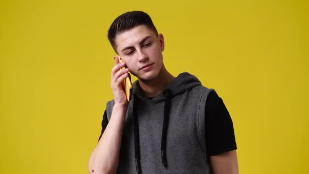 黄色の背景の上に電話を使用して1人の男の4Kスローモーションビデオ 感情の概念 — ストック動画