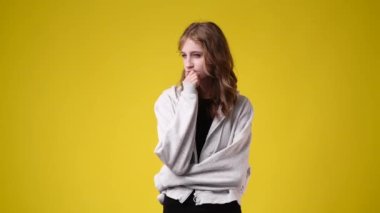 Sarı arka planda düşünceli yüz ifadesi olan bir kızın 4K videosu. Fikirleri olan kız kavramı.