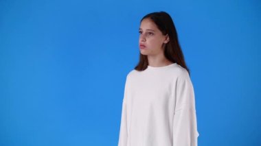 Mavi arka planda bir kızın boş duygularının 4k yavaş çekim videosu. Boş duygu kavramı.