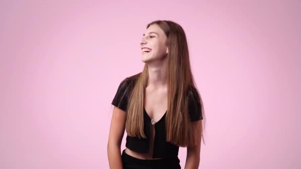 4K慢镜头 一个女孩笑着指着镜头的粉色背景 情绪的概念 — 图库视频影像
