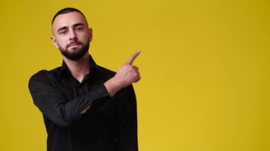 Sarı arka planda sağ tarafı işaret eden bir adamın 4k yavaş çekim videosu. Duyguların kavramı.