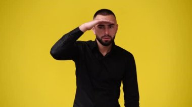 Sarı arka planda kameraya bakan bir adamın 4k yavaş çekim videosu. Duyguların kavramı.