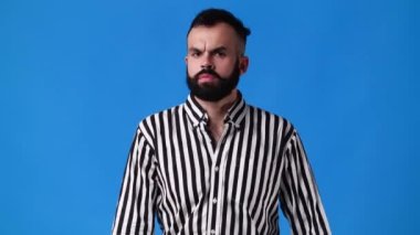 Mavi arka planda çapraz elleri olan bir adamın 4K yavaş çekim videosu. Olumsuz duygu kavramı.