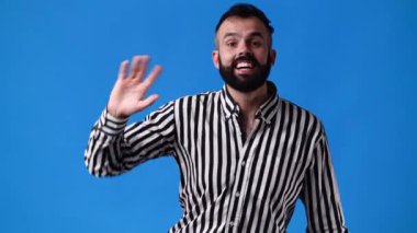 Mavi arka planda el sallayan bir adamın 4K yavaş çekim videosu. Duyguların kavramı.