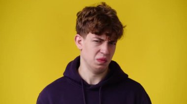 Sarı arka planda negatif yüz ifadesi olan bir adamın 4K yavaş çekim videosu. Olumsuz duygu kavramı.