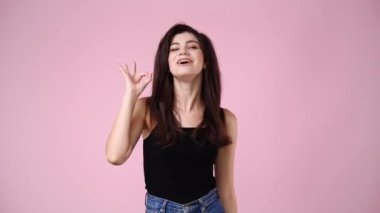 Kızın el işaretini gösteren kameraya gülümsemesinin 4K yavaş çekim videosu. Tamam işareti kavramı.