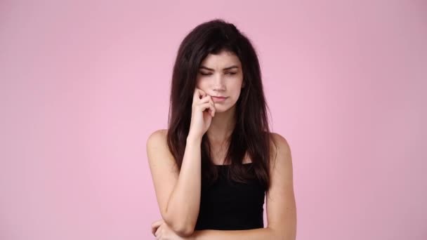 ピンクの背景の上に何かを考えている女性の4Kスローモーションビデオ 感情の概念 — ストック動画