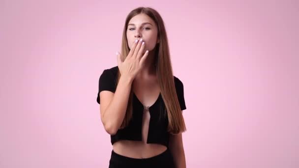 ピンクの背景にエアキスを送る1人の少女の4Kスローモーションビデオ 愛の感情の概念 — ストック動画