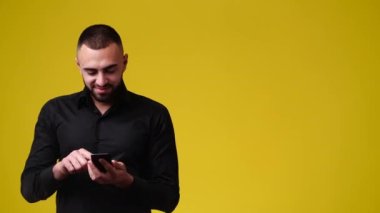 4k yavaş çekim video adam telefon kullanarak ve sarı arkaplan üzerinde sağ tarafı işaret. Duyguların kavramı.