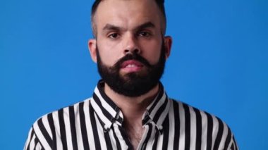 Mavi arka planda gülümseyen adamın 4K yavaş çekim videosu. Duyguların kavramı.