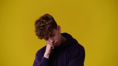 Sarı arka planda bir adamın yüz ifadesinin 4k yavaş çekim videosu. Olumsuz duygu kavramı.