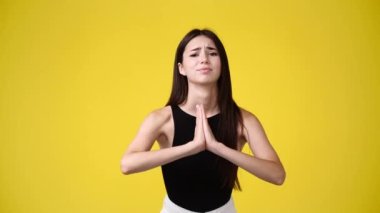 Sarı arka planda yalvaran kızın 4K yavaş çekim videosu. Duyguların kavramı.
