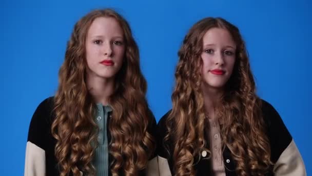 ブルーを背景に思慮深い顔の表情をした双子の女の子の4K動画 アイデアを持つ少女の概念 — ストック動画