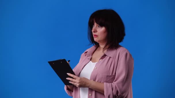一个女人在蓝色背景下记下一些笔记的4K视频 情绪的概念 — 图库视频影像