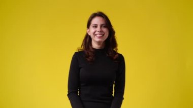 Sarı arka planda gülümseyen tatlı bir kadının 4K yavaş çekim videosu. Duyguların kavramı.