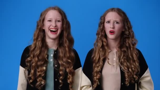 Відео Дівчат Близнюків Різними Реакціями Синьому Фоні Поняття Емоцій — стокове відео