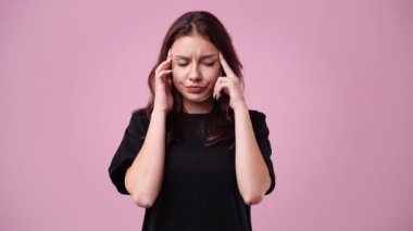 Kızın pembe arka planda parmaklarıyla şakaklarına dokunduğu 4K yavaş çekim videosu. Duyguların kavramı.