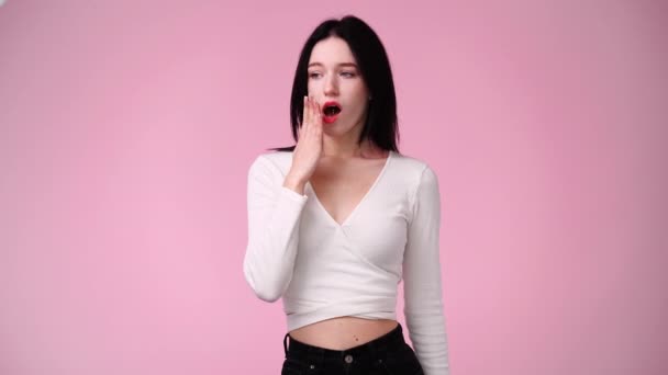 4Kスローモーションビデオの1人の女の子がピンクの背景の上にあくびをしています 感情の概念 — ストック動画