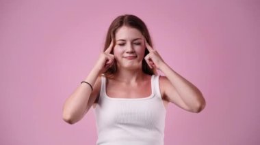 Pembe arka planda düşünceli yüz ifadesi olan bir kızın 4K yavaş çekim videosu. Fikirleri olan kız kavramı.