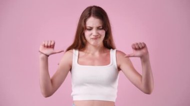 Pembe arka planda parmaklarını gösteren bir kızın 4K yavaş çekim videosu. Olumsuz duygu kavramı.