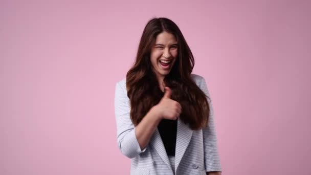 4K的慢镜头 一个女孩在粉色背景上显示大拇指 情绪的概念 — 图库视频影像