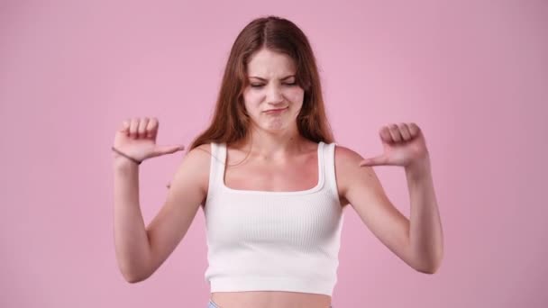 ピンクの背景に親指を示す1人の少女の4Kスローモーションビデオ 負の感情の概念 — ストック動画