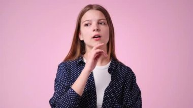 Pembe arka planda düşünceli yüz ifadesi olan bir kızın 4K yavaş çekim videosu. Fikirleri olan kız kavramı.