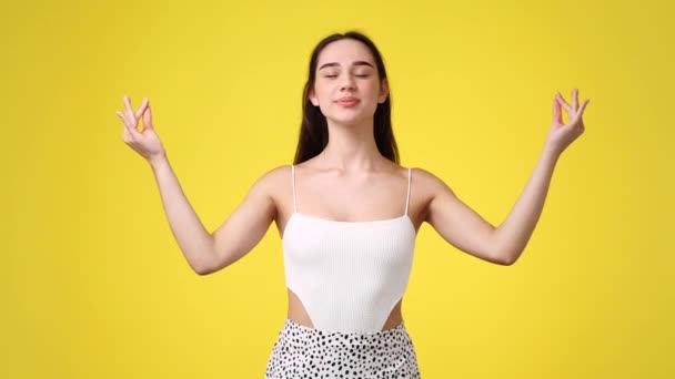 黄色い背景で瞑想している1人の少女の4Kスローモーションビデオ 感情の概念 — ストック動画