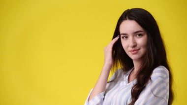 Sarı arka planda poz veren bir kızın 4K videosu. Duyguların kavramı.